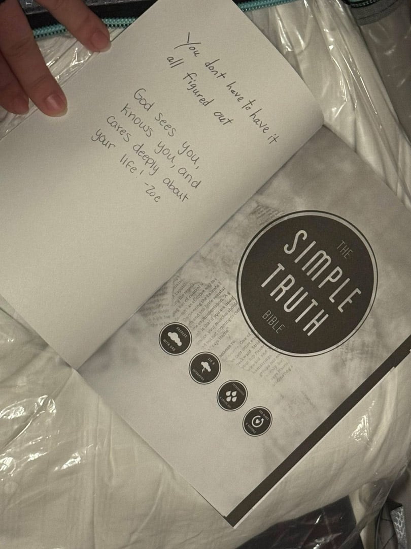 An open book titled "The Simple Truth Bible" lies on plastic packaging. A handwritten note on the left page reads, "You don't have to have it all figured out. God sees you, knows you, and cares deeply about your life. - Zoë.